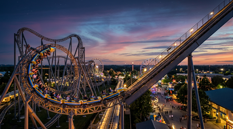 Roller coaster with riders looping and turning at sunset in an amusement park